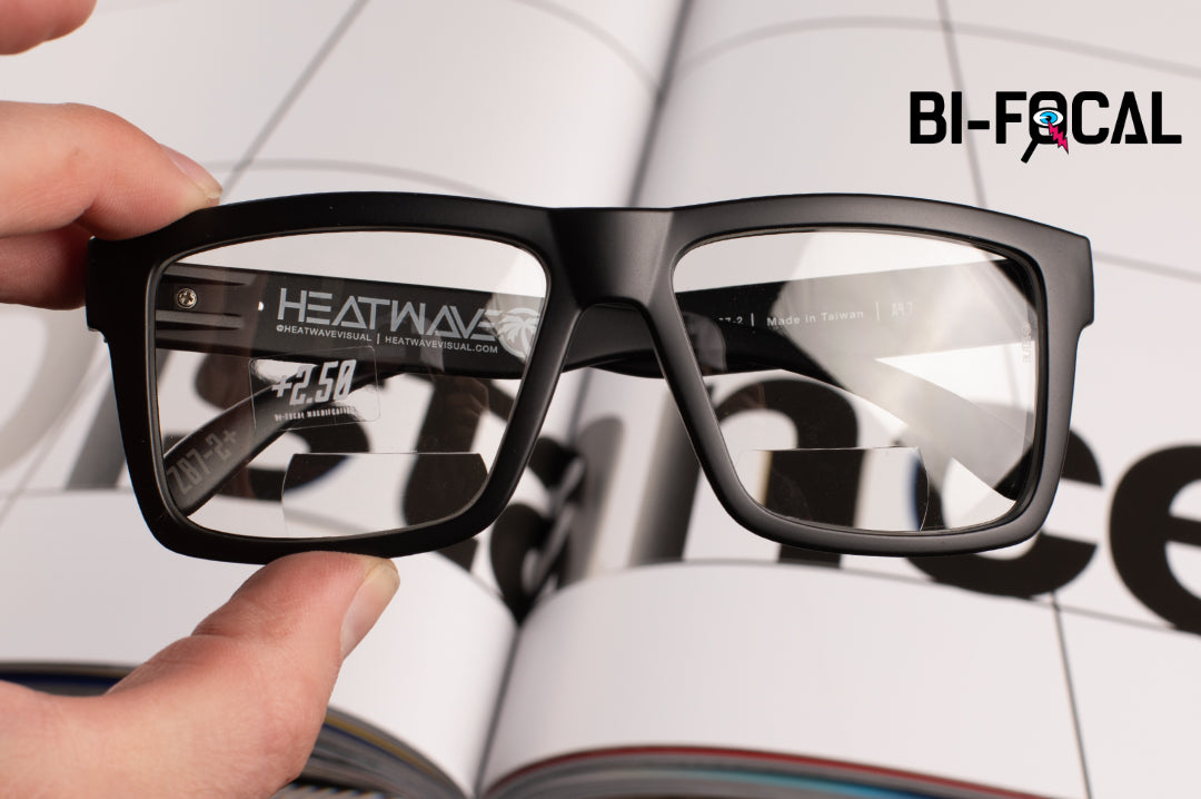 Hand holding the  Heat Wave Visual Vise Z87 Bi-Focal Sunglasses with black frame and clear lenses.
