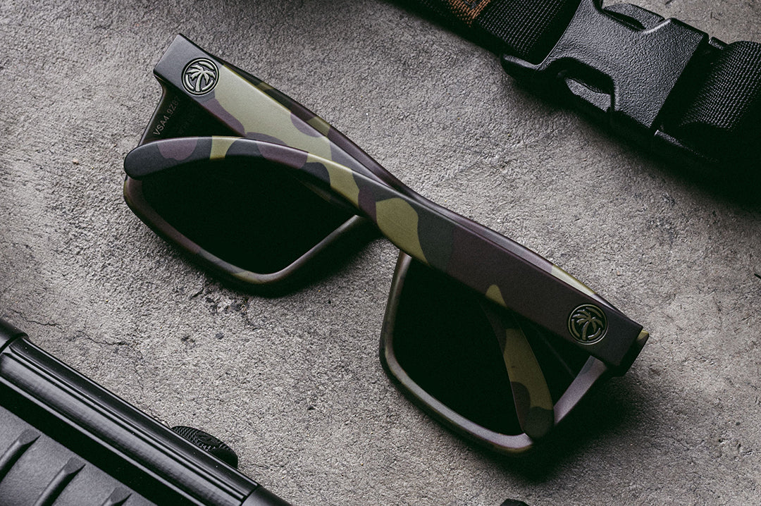 Up close of Heat Wave Visual Vise Z87 Sunglasses with fleck camo frame , ultra black lenses and green emblem