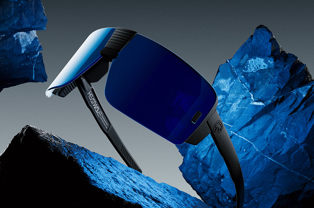 Heat Wave Visual Vector Sunglasses with black frame and galaxy blue lens surrounded by blue rocks.