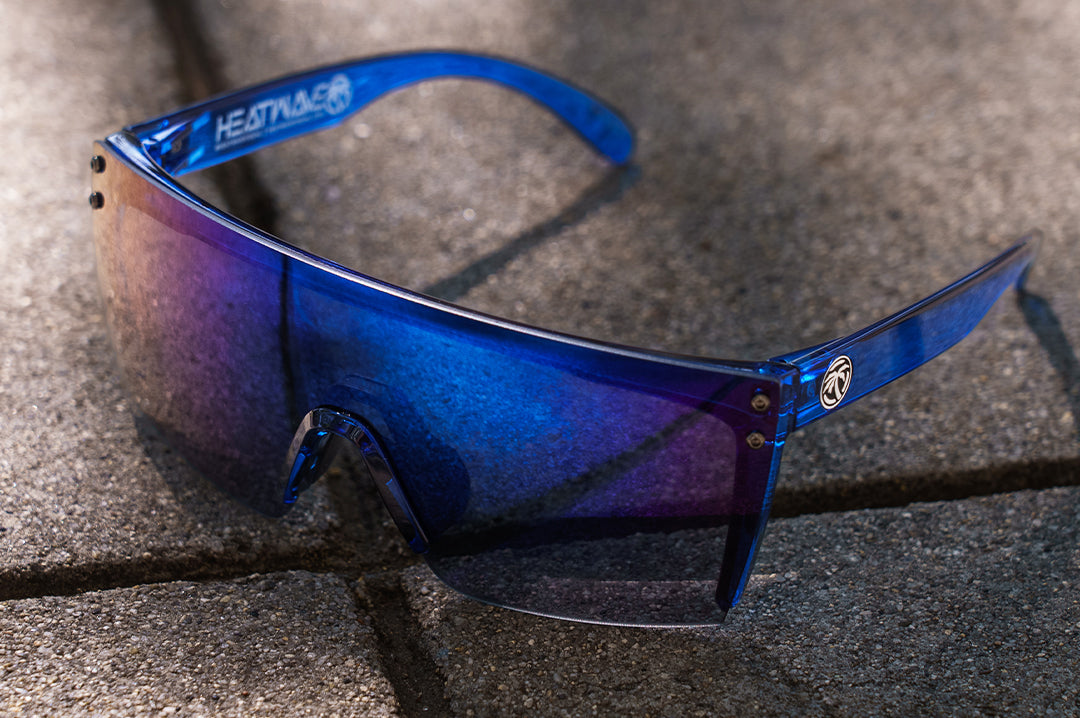 Sitting on the concrete is the Heat Wave Visual Lazer Face Sunglasses with neon blue frames and coastal blue lens.