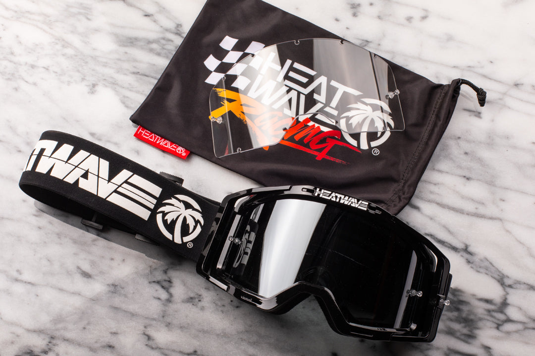 On a table is the Heat Wave Visual MXG 250 Motosport Goggle with a clear replacement lens.