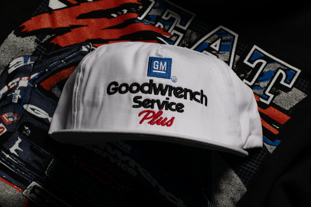 Laying on the ground is the Heat Wave Visual GM Goodwrench hat in white. 