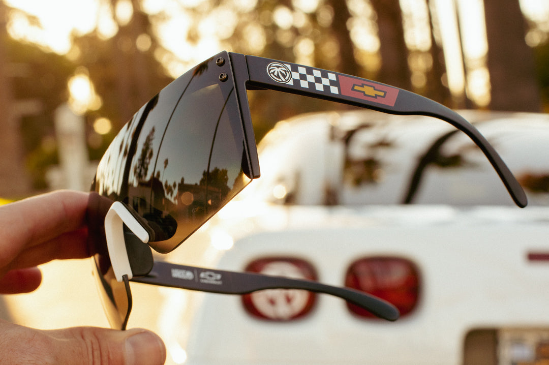 Side view of the Heat Wave Visual Lazer Face Sunglasses with black frame, white nose piece, corvette print arms and black lens.