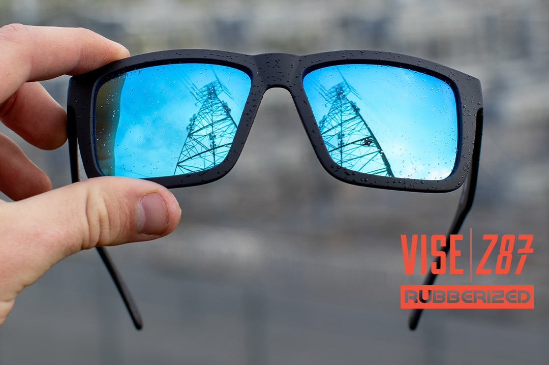 Hand holding the Heat Wave Visual XL Vise Z87 Sunglasses with rubberized frame and galaxy blue lenses.