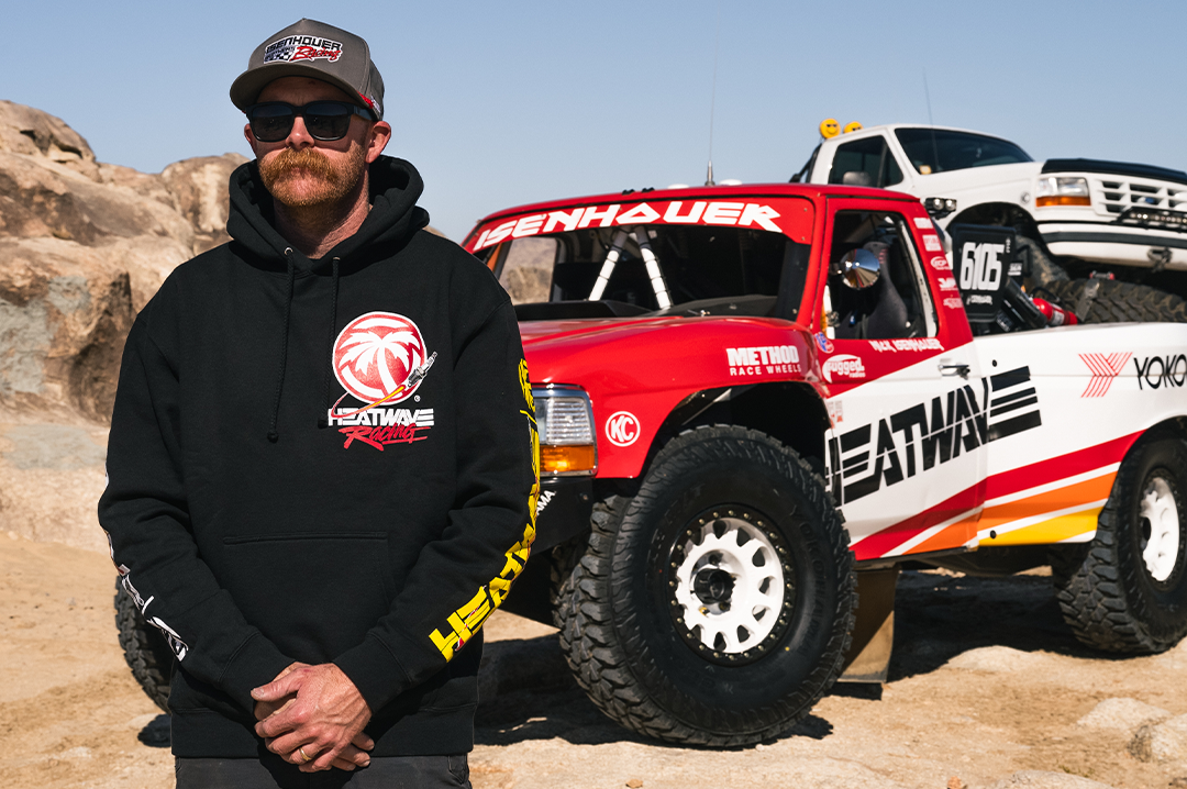 Eisenhouer brother wearing a the new Heat Wave spark racing black hoodie standing in front of a red and white off-road vehicle.