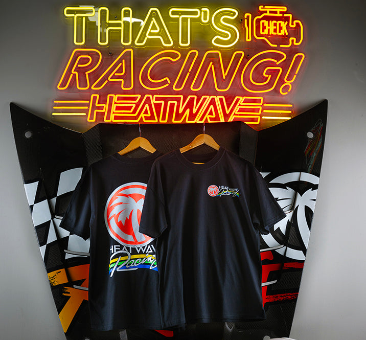 Hanging under a neon sign is the Heat Wave Visual Trading Paint Black T-shirt.