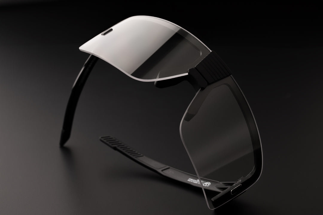 Heat Wave Visual XL Vector Sunglasses with black frame and clear lens lying on it's side on a table.