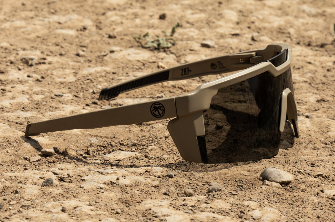 Heat Wave Visual Future Tech Sunglasses with tan frame and black lens on a dirt path. 