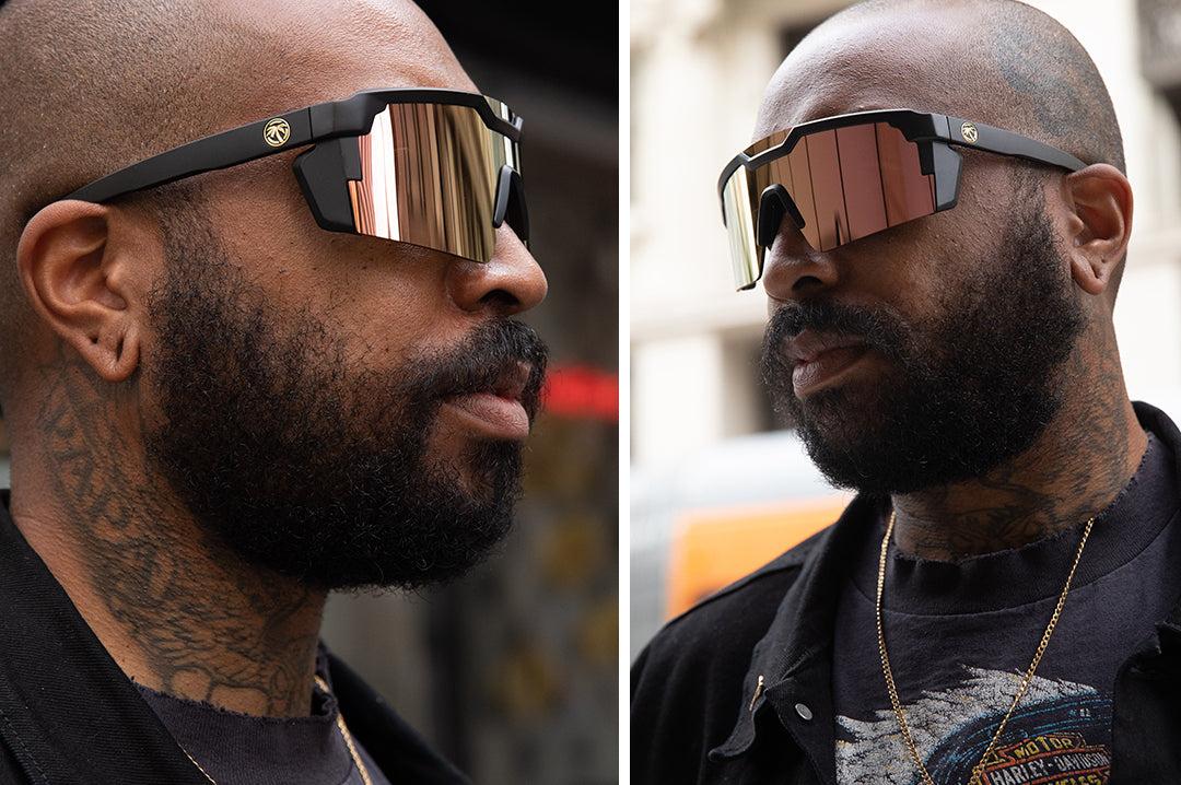 Bearded tattooed man wearing Heat Wave Visual Future Tech Sunglasses with black frame and rose gold lens.