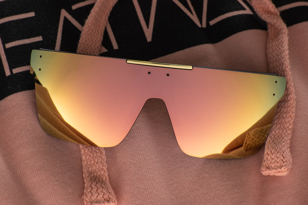 Heat Wave Visual Quatro Sunglasses with black frame and rose gold lens lying on a sweatshirt.