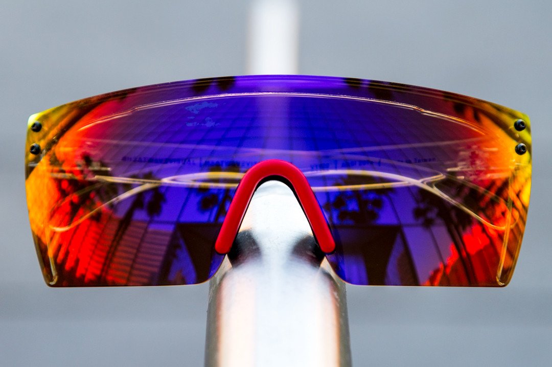Heat Wave Visual Lazer Face Z87 Sunglasses with black frame and atmosphere red blue lens sitting on a metal hand rail.