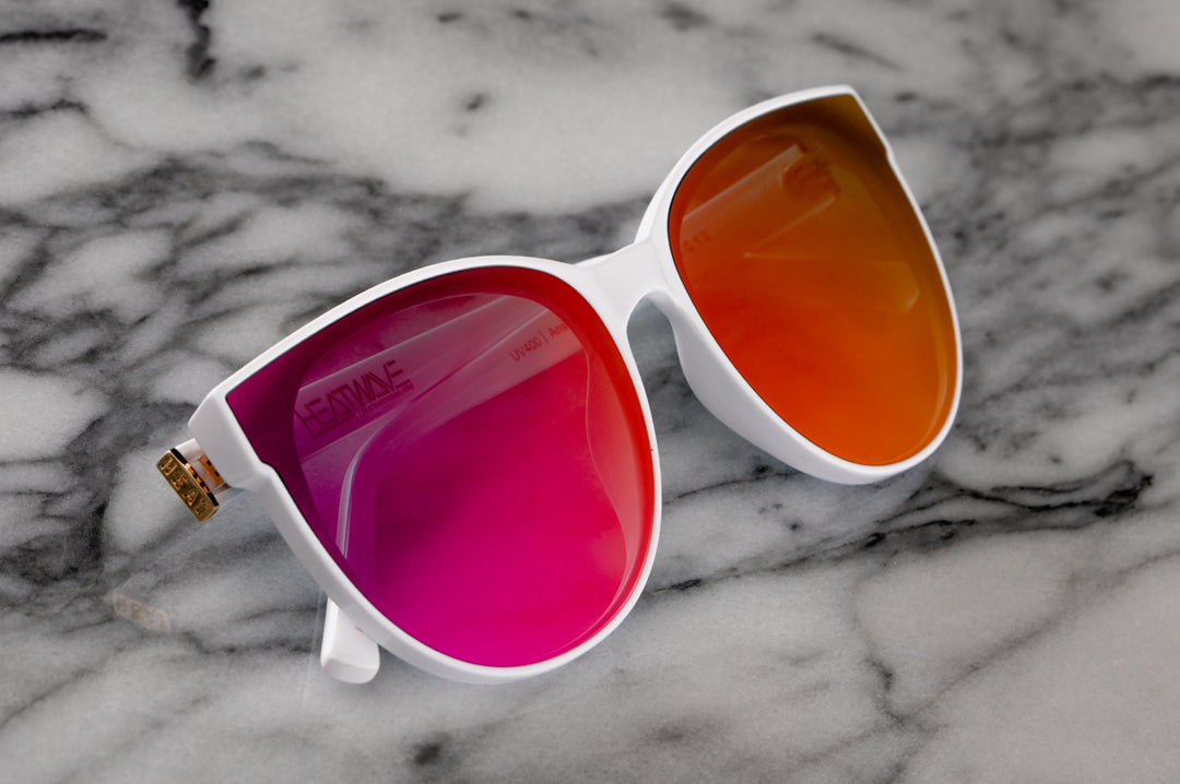 Close up of Heat Wave Visual Womens Carat Sunglasses with white frame and spectrum pink lenses.