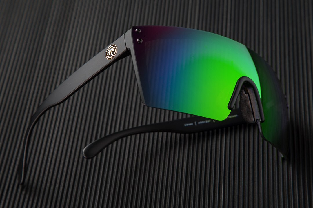 Side view of Heat Wave Visual Lazer Face Z87 Sunglasses with black frame and piff green lens on black table. 