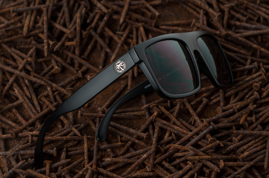 Heat Wave Visual Z87 Regulator Sunglasses with black frame and polarized black lenses laying in a bed of rusty nails.