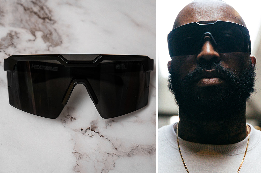 Close up of bearded man wearing Heat Wave Visual Future Tech Sunglasses with black frame with SOCOM print arms and black lens.