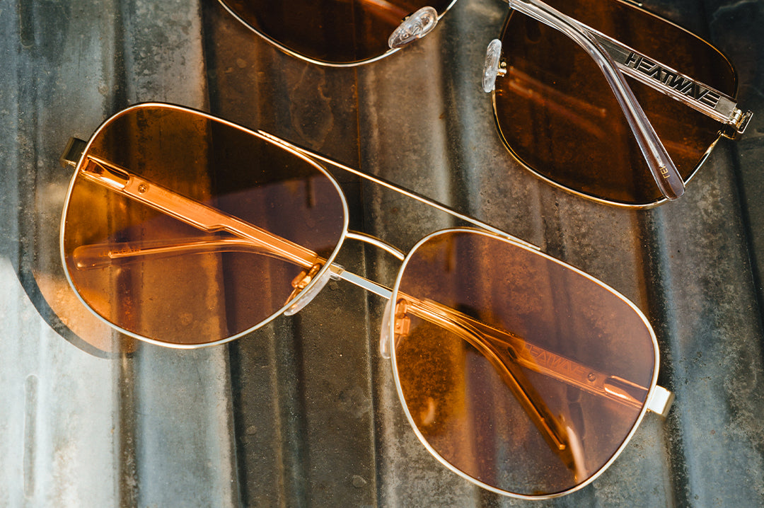 Aviator sunglasses with gold frames and Amber lenses on a textured surface