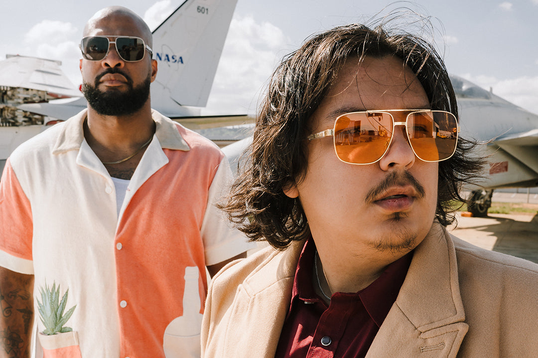 Two men wearing Aviator sunglasses with a F-14 airplane in the background