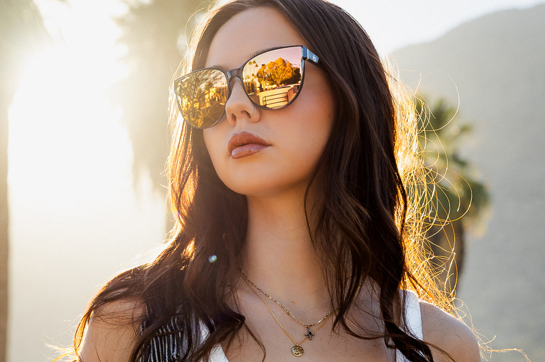 Young women outside wearing the Heat Wave Visual Carat Sunglasses with quartz frames and rose gold lenses.