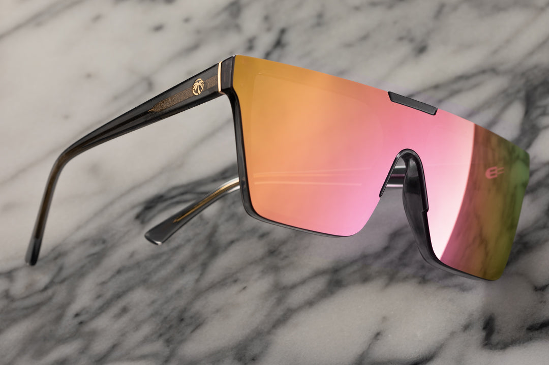 Lying on a marble slab is the Heat Wave Visual Clarity Sunglasses with quartz frames and rose gold lens.