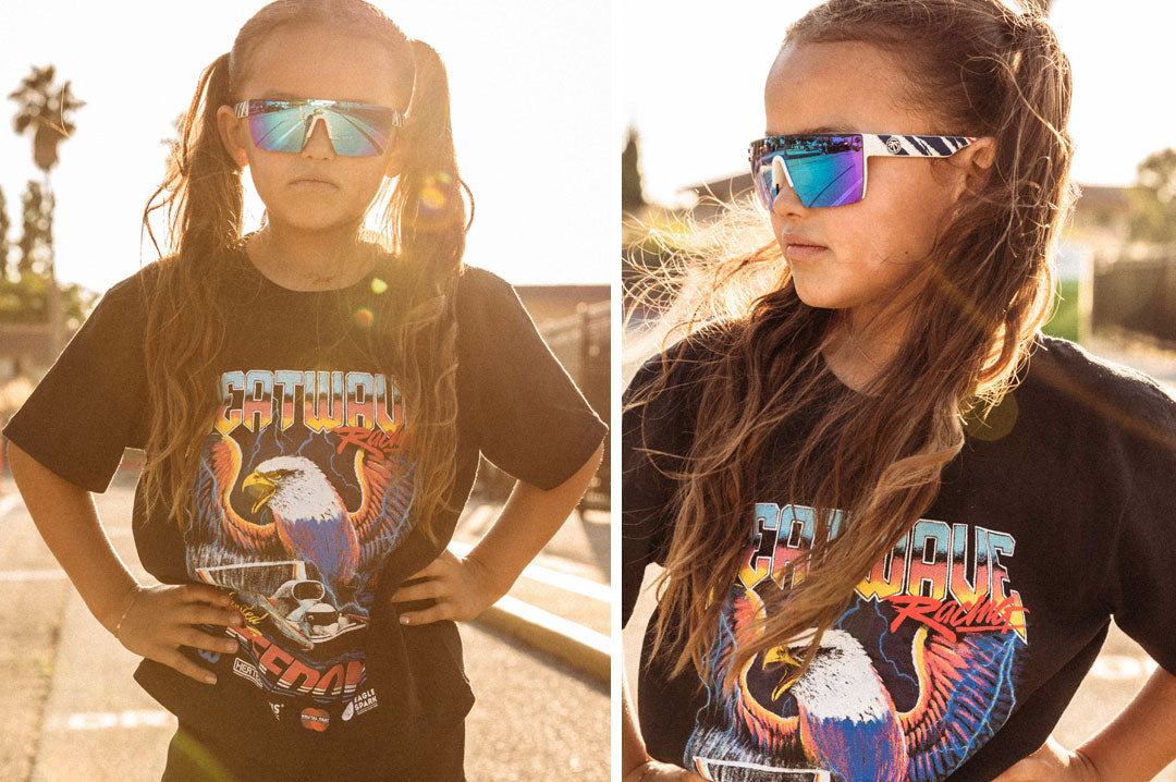 Young girl wearing the Heat Wave Visual Lazer Face kids sunglasses white frame, red white and blue print arms and galaxy blue lens.