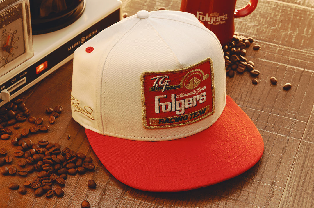 The HWV 5 Panel Hat: Hendrick Motorsports | Tim Richmond 25 Folgers on a wood table