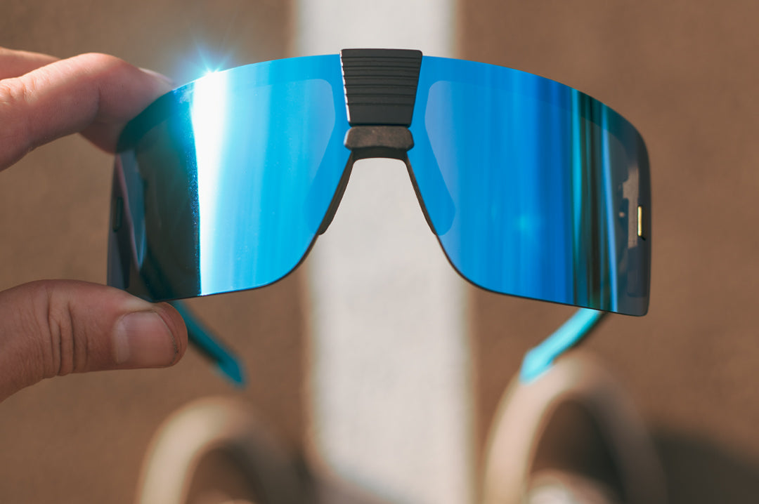 Hand Holding a pair of Heat Wave Visual Vector Sunglasses with black frame and galaxy blue lens.