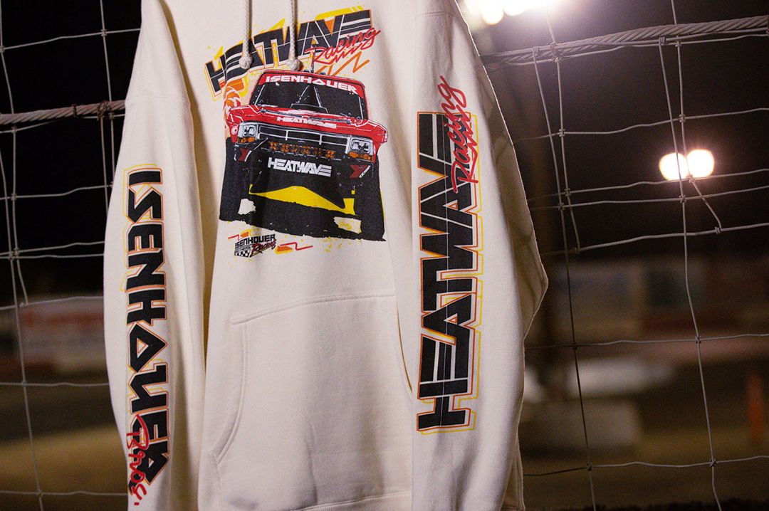 The Heat Wave Visual Isenhouer Racing Sweatshirt hangin on a wire fence.