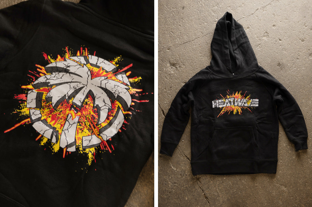 Lying on the concrete floor is the Heat Wave Visual Explosion Sweatshirt in black. 