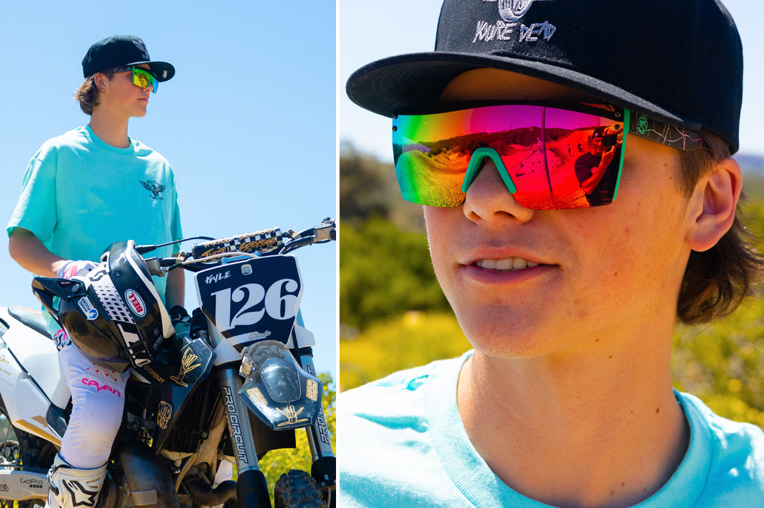 Male dirt biker wearing Heat Wave Visual Lazer Face Sunglasses with aqua frame, shreddy print arms and spectrum pink yellow lens.