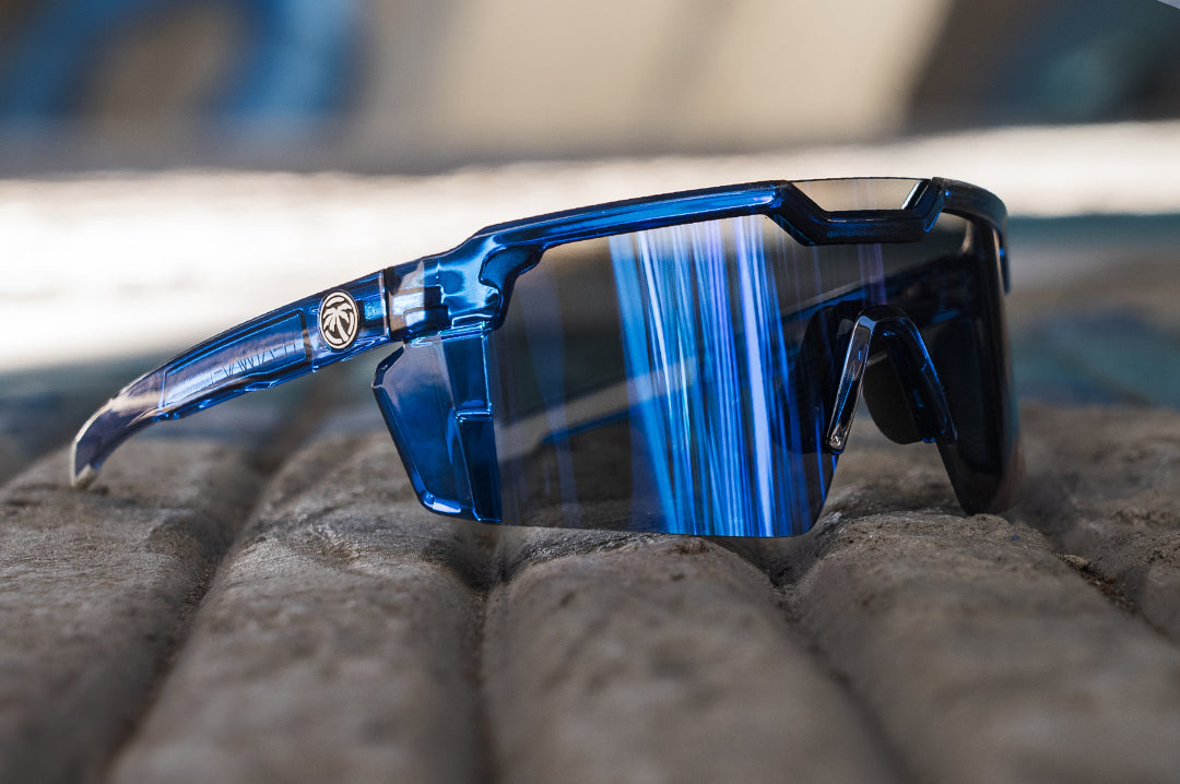 Heat Wave Visual Future Tech Sunglasses with neon blue frame and coastal blue lens laying on the ground.