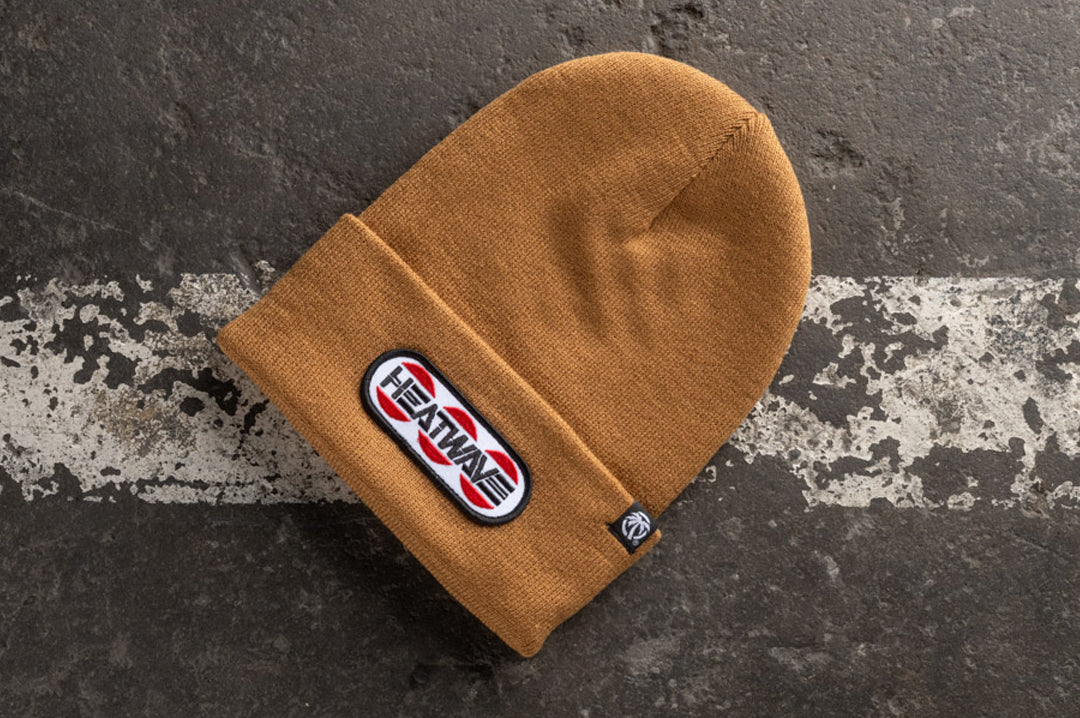 Lying on the ground is the Heat Wave Visual Butterfly Oatmeal Beanie.