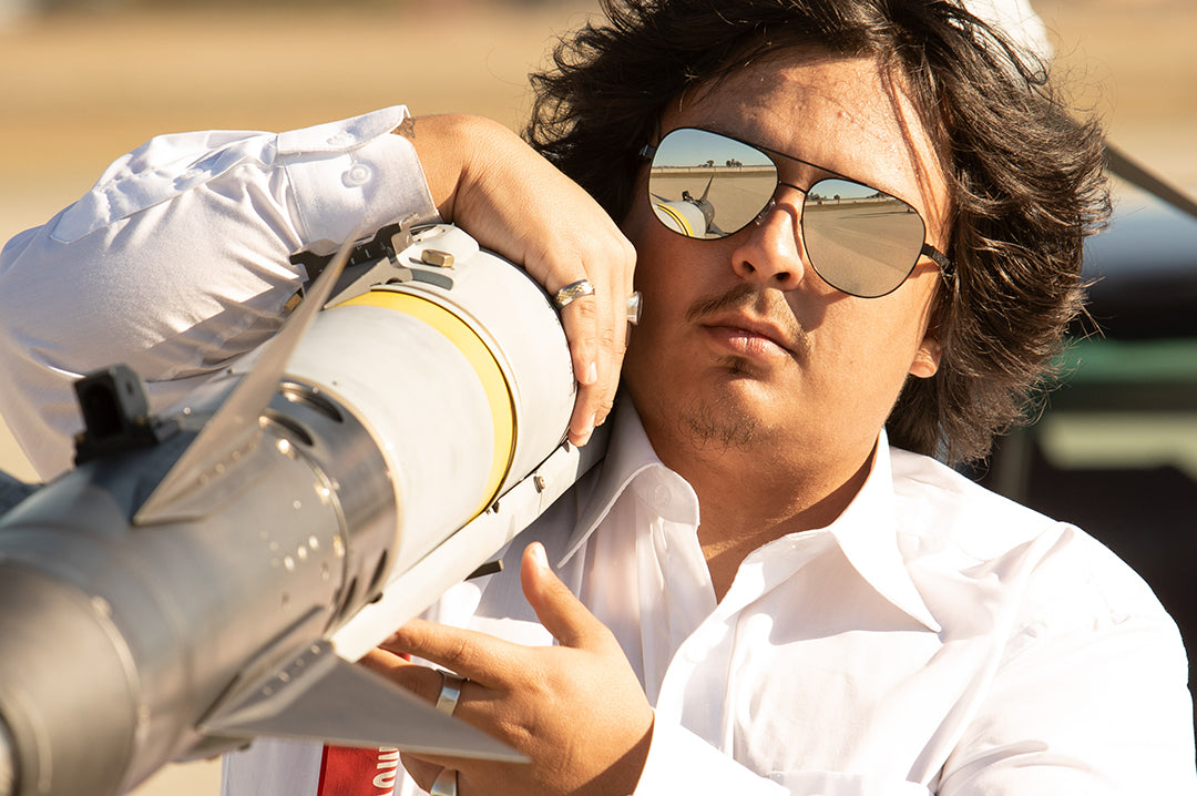 Zack carrying a missile while rocking the Heat Wave Visual Incline Sunglasses with gun metal frame and silver lenses.