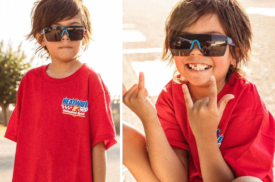 Young kid wearing the Heat Wave Visual Lazer Face kids sunglasses blue frame, static print arms and black lens.