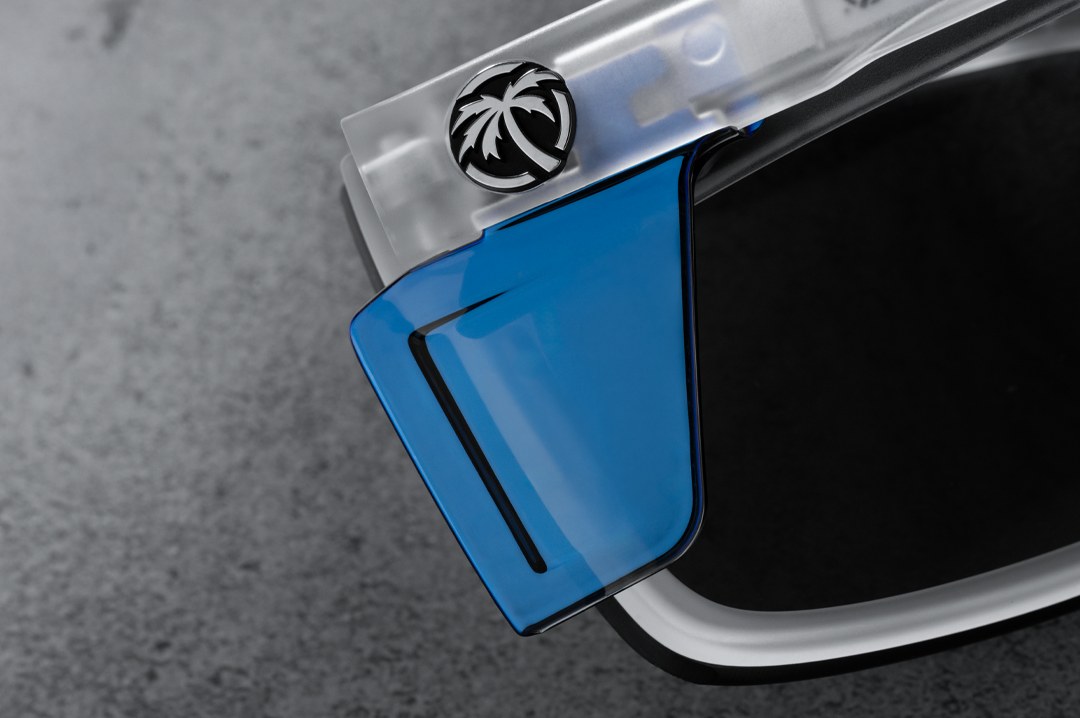 Close up backside shot of the Performance Vise Sunglasses: Vapor Frost Frame Coastal Lens Z87+ with blue side shields on a concrete table.
