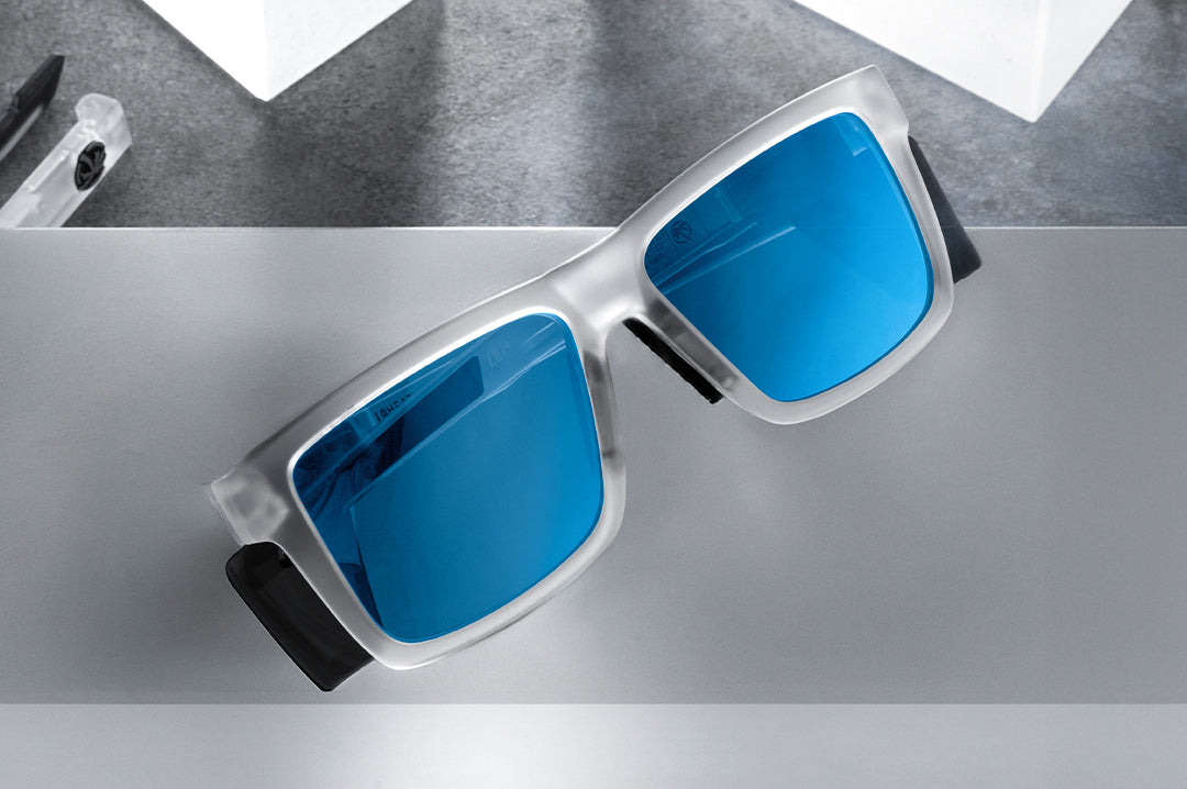 Indoor studio shot of the Performance Vise Sunglasses: Vapor Frost Frame Coastal Lens Z87+ on a concrete block.