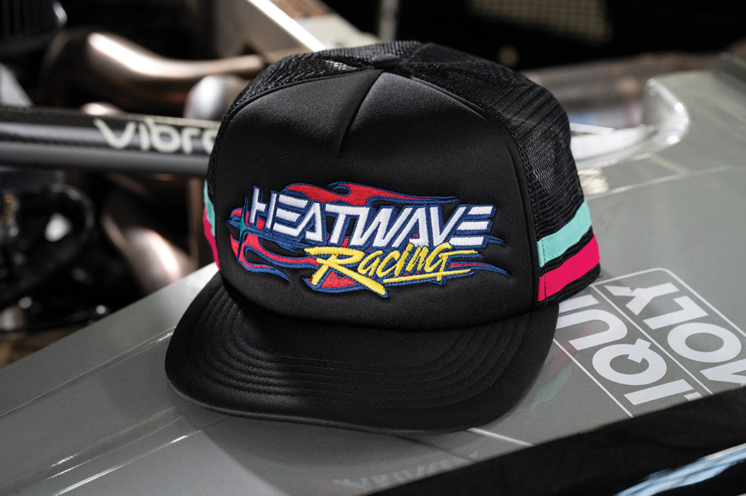 The Black Heat Wave Y2K Racing Hat sitting on equipment 