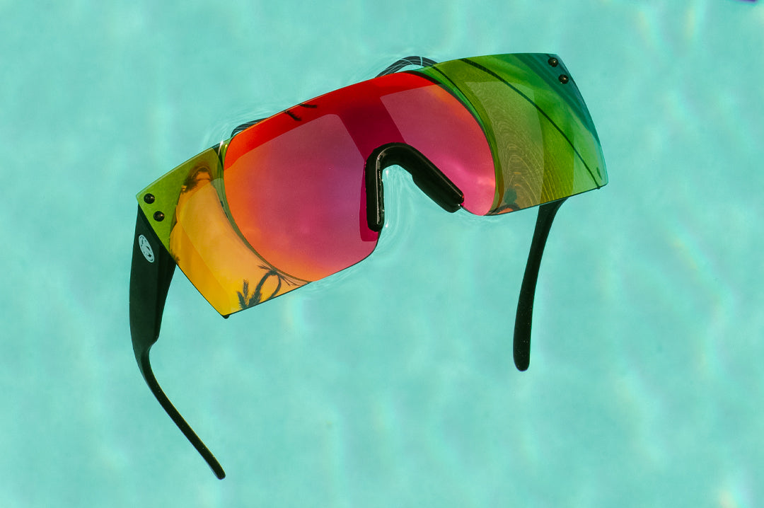 Heat Wave Visual H2O Lazer Face Sunglasses with black frame and atmosphere red blue lens floating in a pool.