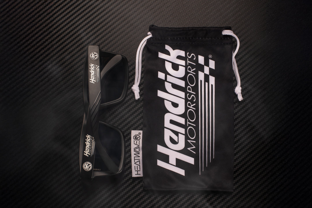 Lying on a table is the Hendrick Motorsports x Heat Wave Visual Vise Sunglasses and matching microfiber.