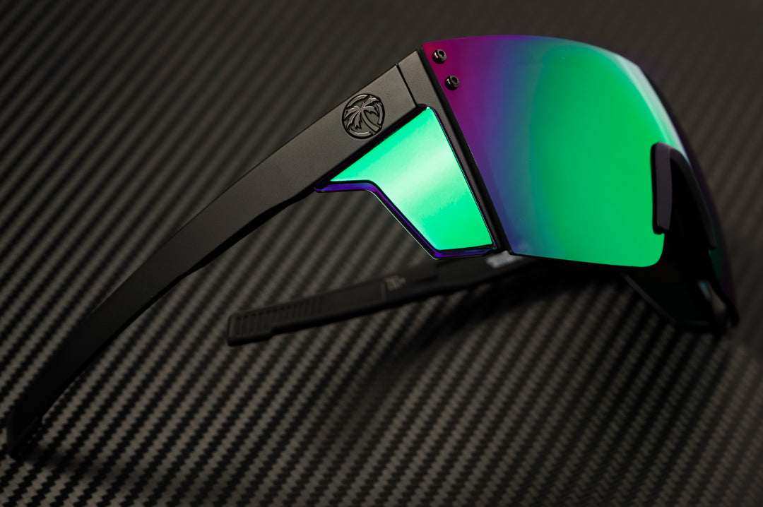 Laying on it's side is the  Heat Wave Visual Performance Lazer Face Sunglasses with black frame, piff green blue lens and matching colored side shields.