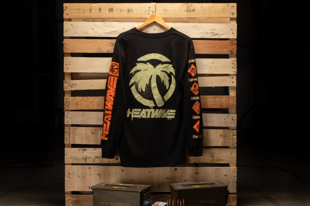 Hanging on a pallet is the Heat Wave Visual Ammo Can Long sleeve with Spay paint graphic on the back. 
