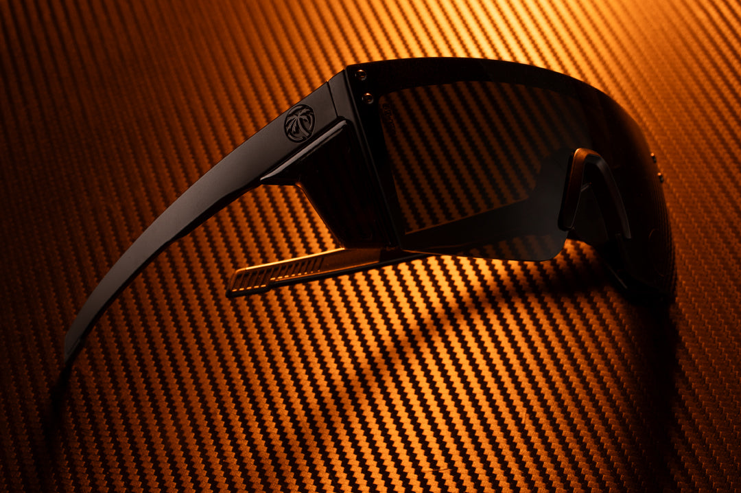 Laying on a table is the Heat Wave Visual XL Lazer Face Ultra Black Sunglasses.