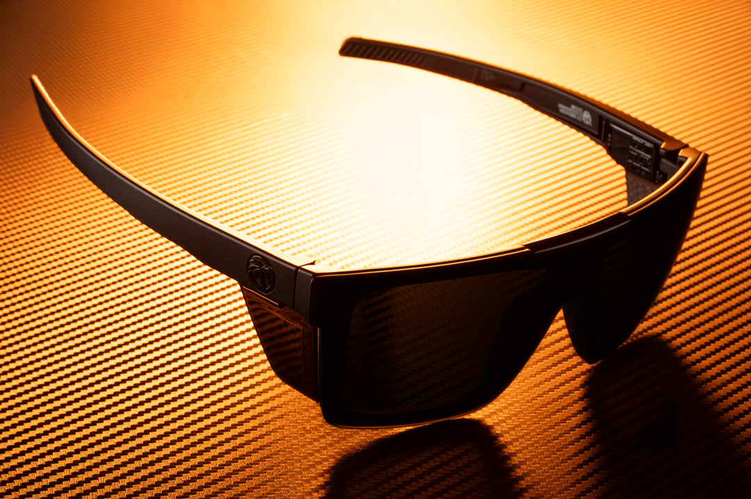 Laying on a table is the Heat Wave Visual Performance Quatro Ultra Black Sunglasses. 