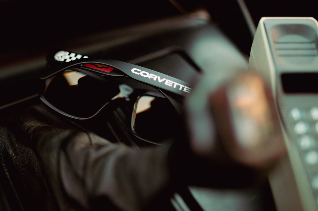 Laying on the center console is the Heat Wave Visual Vise Sunglasses with black frame, corvette print arms and gold lenses.