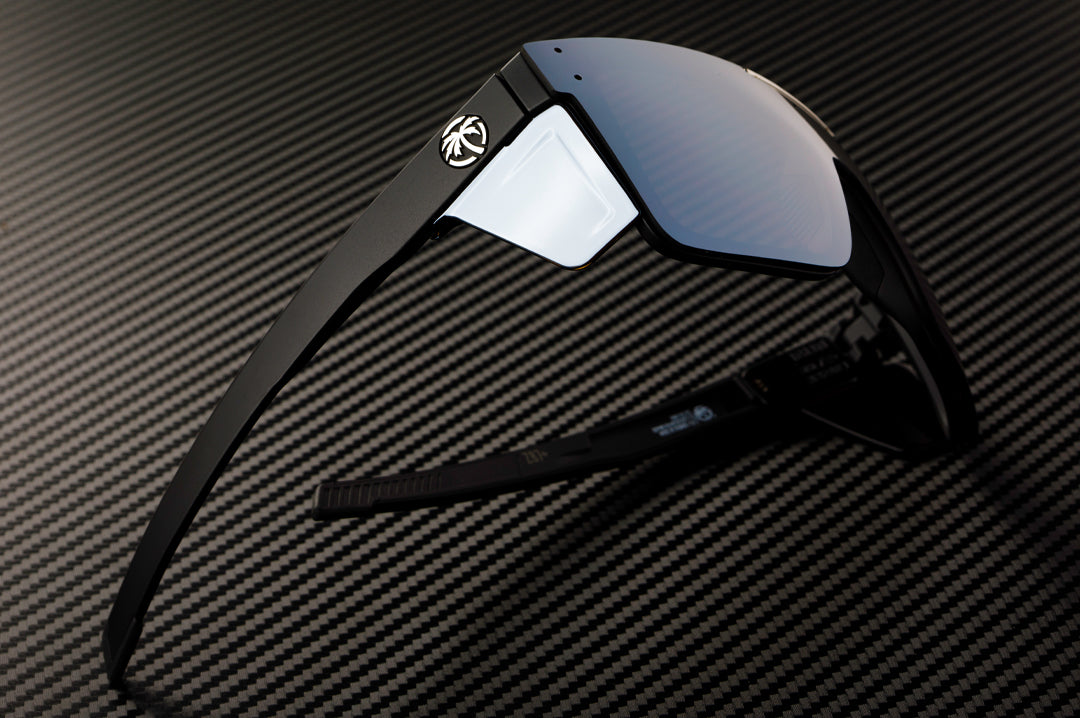 On a table is the Heat Wave Visual Performance Quatro Sunglasses with black frame, silver lens and matching colored side shields. 