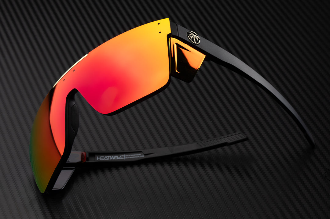 Laying on it's side is the Heat Wave Visual Performance Quatro Sunglasses with black frame, red/orange lens and matching colored side shields.