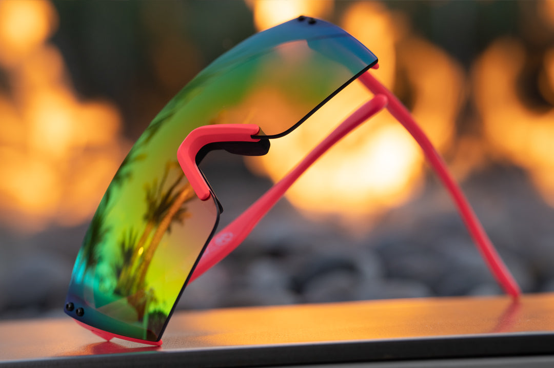 Lying sideways on a table is Heat Wave Visual Lazer Face Z87 Sunglasses with pink frame, standup print arms and spectrum pink yellow lens. 