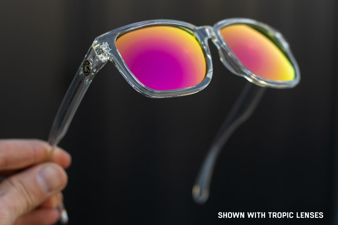 Hand holding Heat Wave Visual Apollo Sunglasses with clear frame and tropic pink yellow lenses.