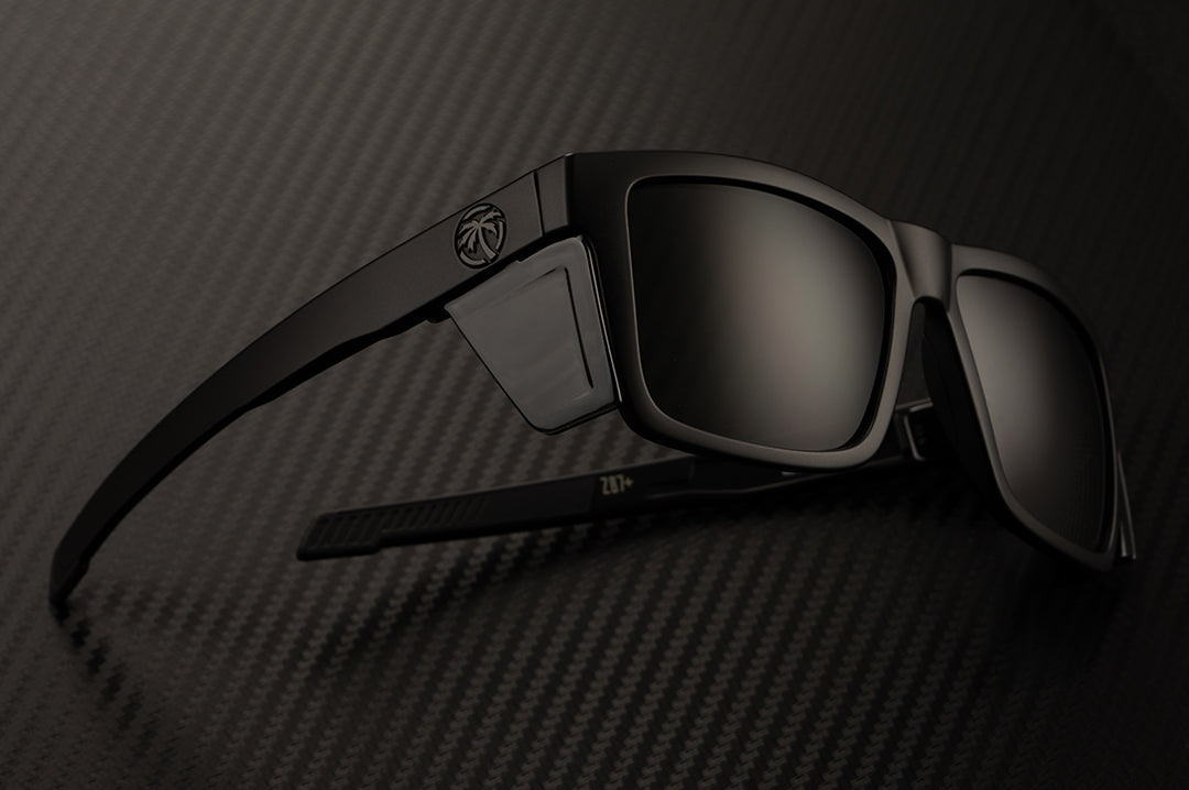 Laying on it's side is the Heat Wave Visual Performance XL Vise Sunglasses with black frame, black lenses and black side shields.