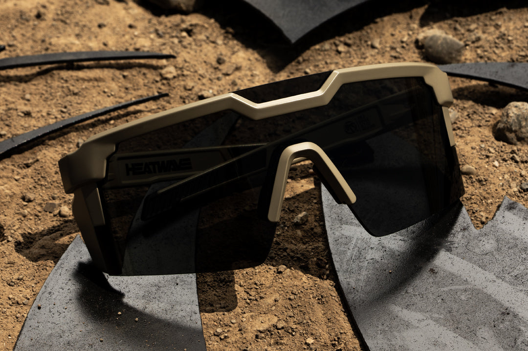 Heat Wave Visual Future Tech Sunglasses with tan frame and black lens sitting on dirt.