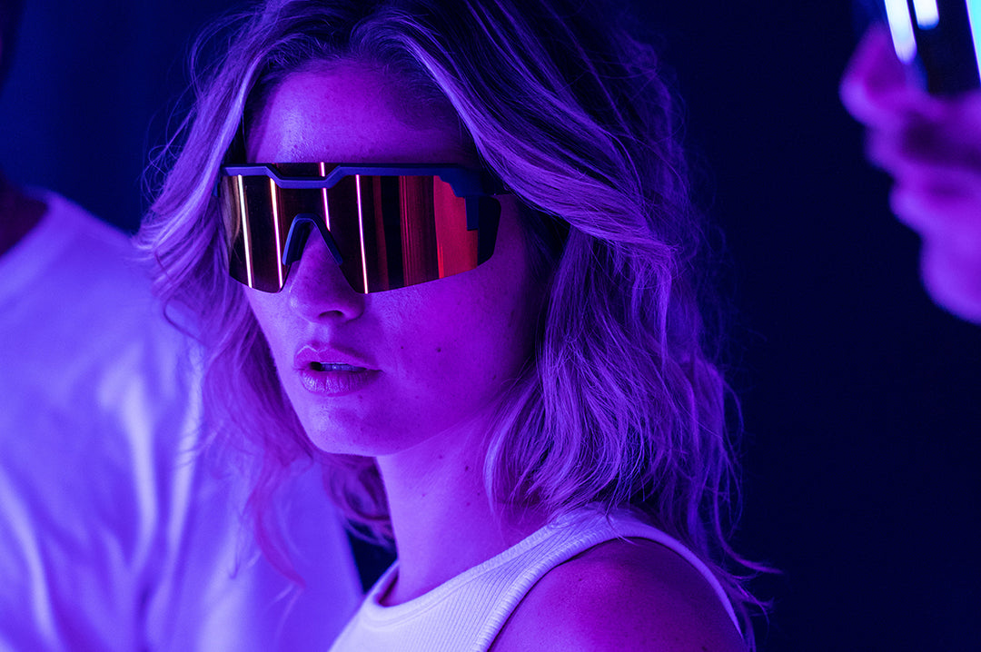 Young women at the club wearing Heat Wave Visual Future Tech Sunglasses with black frame and firestorm red lens.